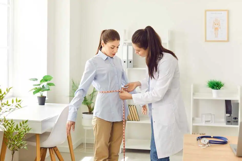 Healthcare provider measuring a woman’s waist during a weight management consultation in in Tulsa, OK